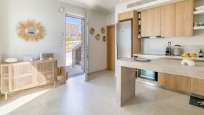 A modern kitchen with wooden cabinets, a built-in oven, and a large window. - Spick & span in Paros island (Aspro Chorio)