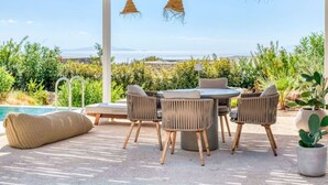 An outdoor seating area with a pool, wicker chairs, and a view of the landscape. - Spick & span in Paros island (Aspro Chorio)