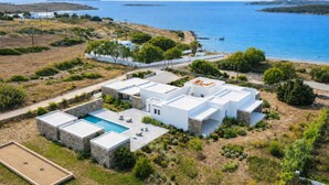 A modern villa with a swimming pool, white exterior, and a view of the sea.