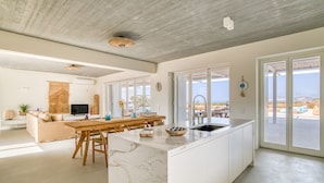 A spacious kitchen with a large island, a dining area, and a view of the sea.
