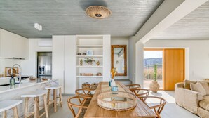 A modern kitchen with white cabinetry, a built-in oven, and a large island with bar stools.