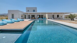A modern house with a swimming pool, outdoor seating, and a view of the landscape.