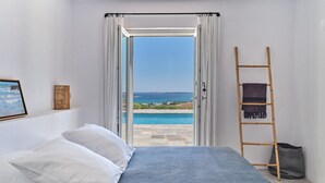 A bedroom with a bed, a view of a pool and the sea, a ladder, and a framed picture on the wall. - Villa Tchi Tcha - Naoussa Bay (Kamares Naousas)