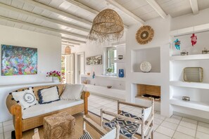 Una sala de estar acogedora con un sofá de mimbre, una lámpara colgante tejida y una chimenea.