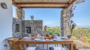 Un área de comedor al aire libre de piedra con una mesa preparada para dos personas, una estatua de Buda y vistas del paisaje.