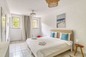 Una habitación de hotel con una cama, una ventana, una puerta y un cuadro en la pared.
