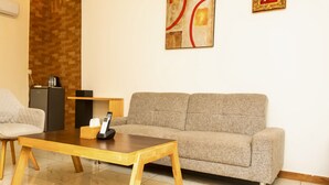A living room with a sofa, a chair, a coffee table, and a small table with a remote control. - HOTEL GOLDEN PLAZZA CONAKRY (Conakry)
