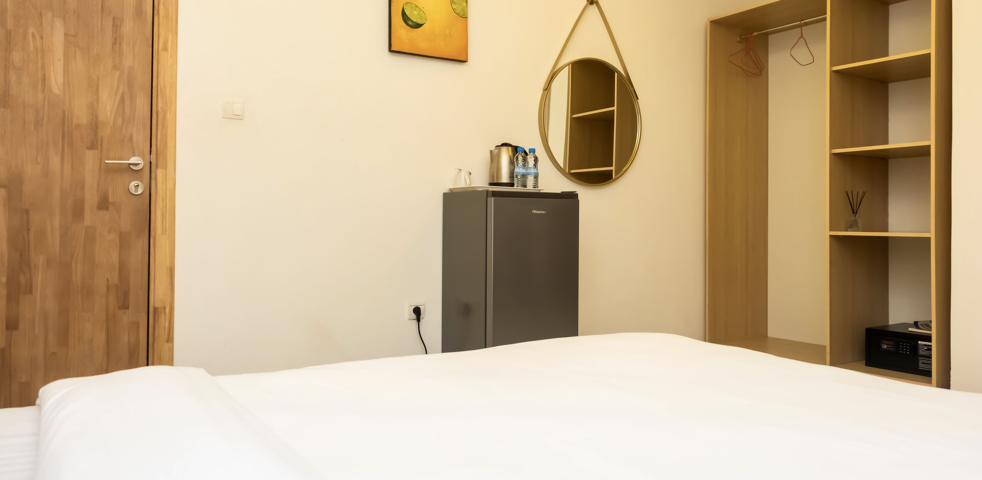 Ein Hotelzimmer mit Bett, Minibar, Spiegel und Kleiderschrank.