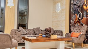 A modern living room with a tufted sofa, a wooden coffee table, and a decorative horse sculpture. - HOTEL GOLDEN PLAZZA CONAKRY (Conakry)