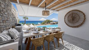 A dining area with a table set for four, overlooking a pool and the sea. - Black Pearl Villa - Sea Front (Ampelas)