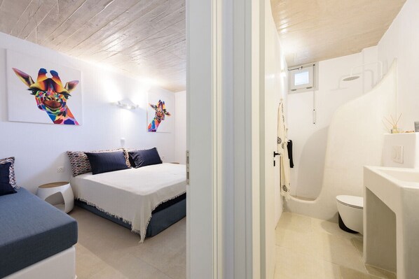 A bedroom with a bed, bedside tables, and two wall-mounted artworks.