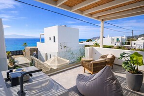 A balcony with a view of the sea, a white building, wicker furniture, and a potted plant. - Akoya Pearl Villa - Sea Front (Ampelas)