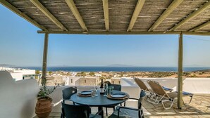 A terrace with a table set for two, overlooking a coastal landscape. - Folia House - Overlooking (Aspro Chorio)