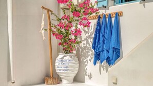 A white wall with a wooden door, a white vase with a quote, and blue towels hanging on a rack. - Onikos House - South Gem (Aliki)