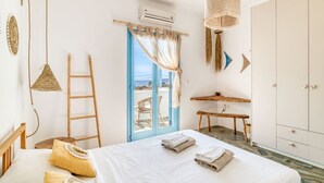 A bedroom with a bed, a desk, a wardrobe, and a view through a door. - Onikos House - South Gem (Aliki)