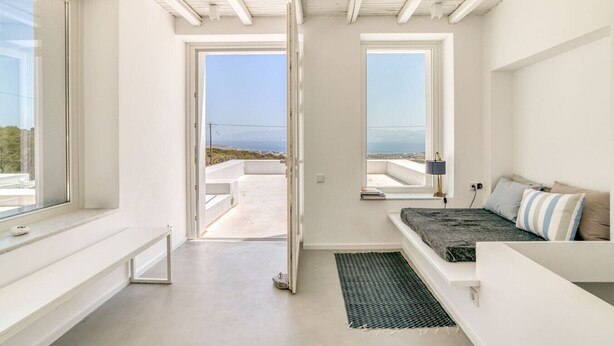 A modern room with a bed, a window, and a view of the sea. - Luxury standards in great location (Kostos)