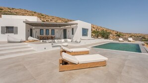 Eine moderne Villa mit Pool, Sitzgelegenheiten im Freien und Essbereich.