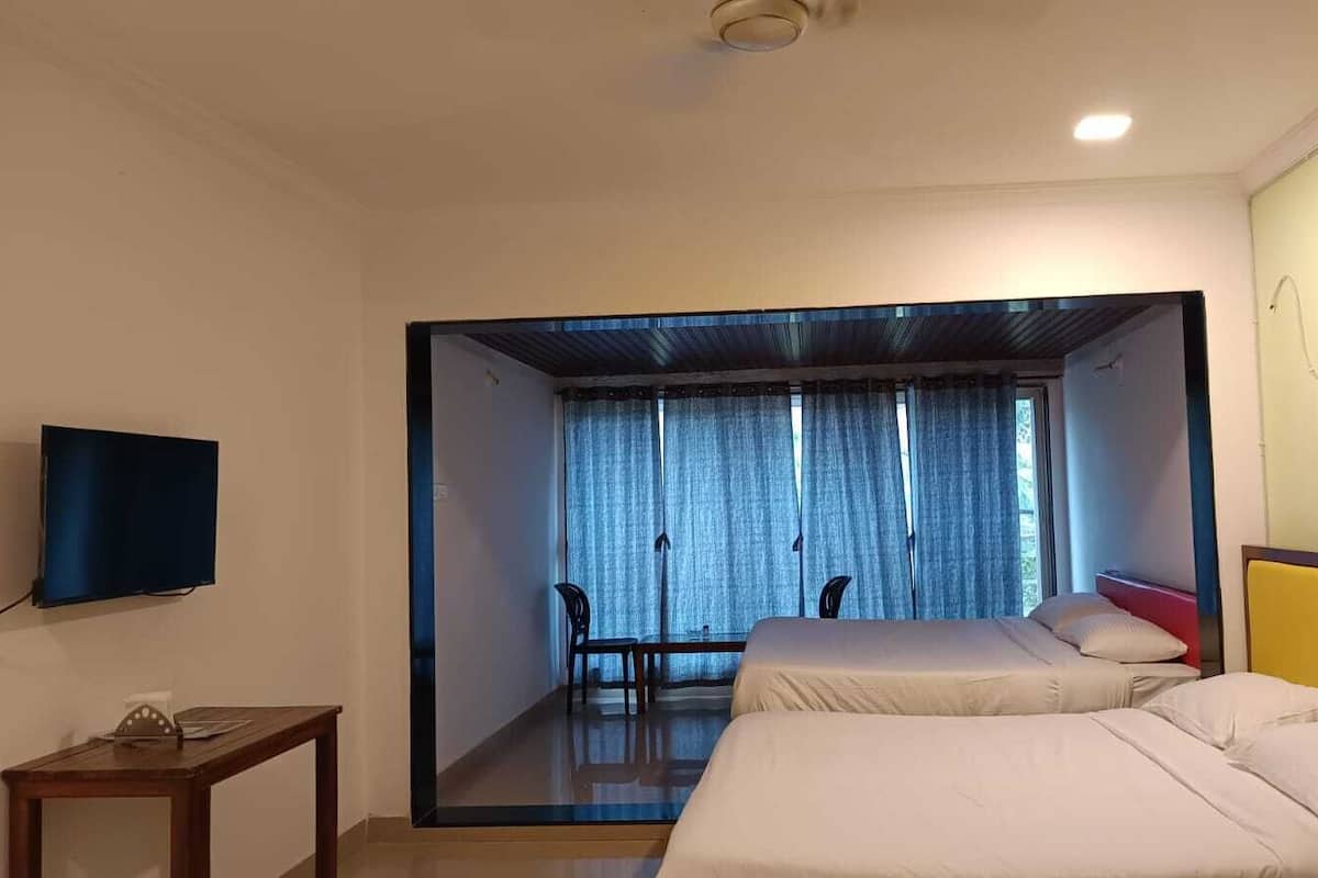 A hotel room with two beds, a television, a desk, and a view of a balcony.