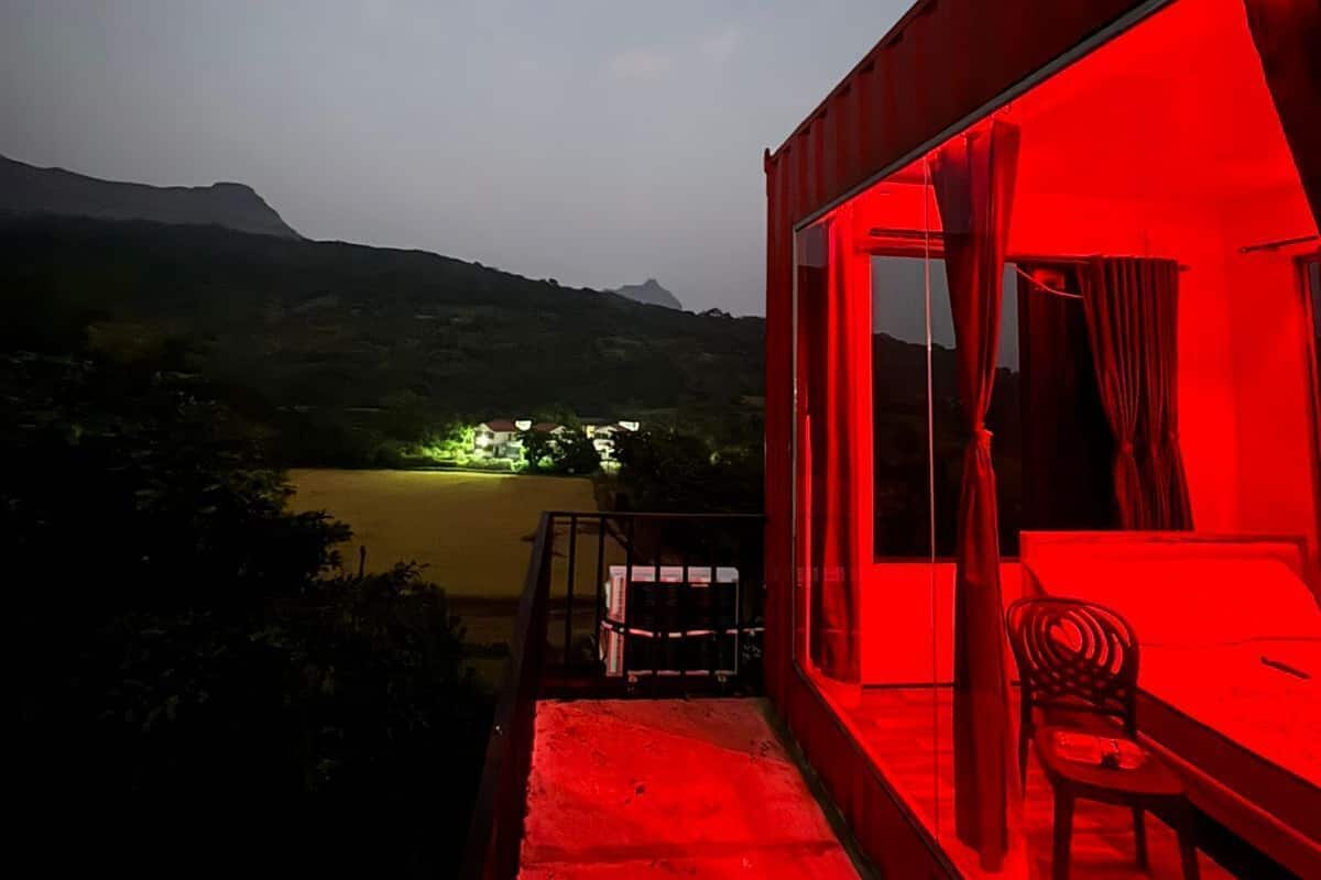 A balcony with a red-lit interior, overlooking a valley with distant lights.