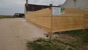 Une clôture en bois avec une pancarte indiquant « GÎTE » et « Faites comme chez vous ! ».