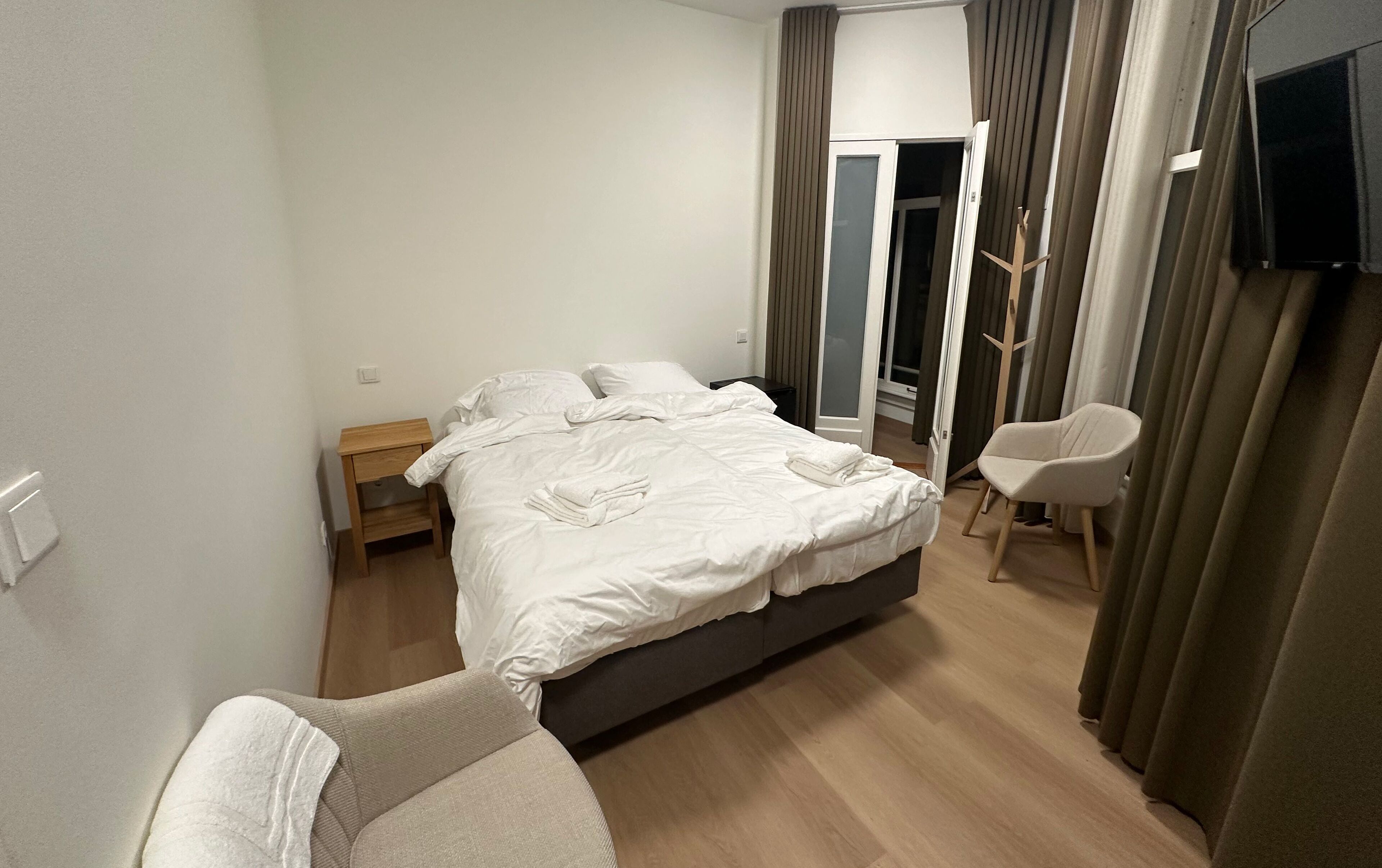 Une chambre d’hôtel avec un lit, une chaise, une table de chevet et un téléviseur.