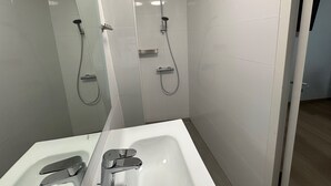 Ein modernes Badezimmer mit einem weißen Waschbecken, einem Spiegel und einer Dusche mit Duschbrause.