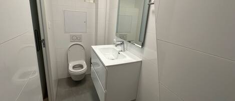 Un baño moderno con inodoro, lavamanos y espejo.