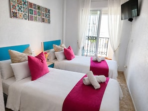 Een hotelkamer met twee bedden, een aan de muur bevestigde televisie en een balkon met uitzicht.