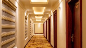 A hotel hallway with a patterned carpet, wooden doors, and recessed lighting. - Legacy Hotel Alchi (Alchi)