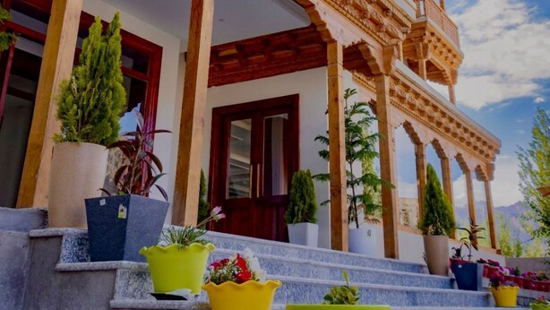 A traditional building with ornate wooden balconies and a covered entrance. - Legacy Hotel Alchi (Alchi)