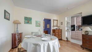 A dining area with a round table set for four, wooden chairs, a lamp, and artwork on the walls.