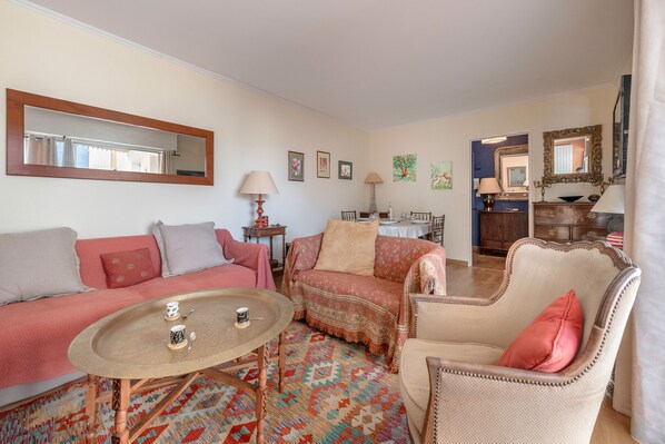 A living room with a sofa, armchair, coffee table, and a patterned rug.