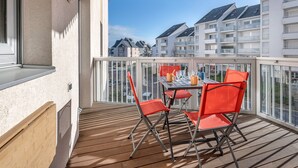 A balcony with a table and chairs, overlooking a residential area with multiple buildings.