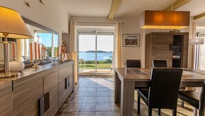 A modern kitchen with a large island, a dining area with a view of the sea, and a spacious living area with a large window.