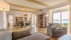 A spacious living area with a large window, a dining area, and a kitchen.