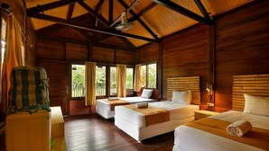 A wooden cabin with three beds, a wooden ceiling, and large windows. - Plengkung Lodge G-land (Kalipait)