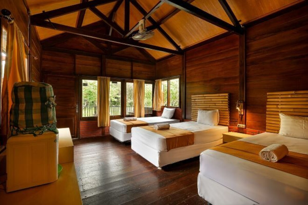 A wooden cabin with two beds, a chair, and a table.