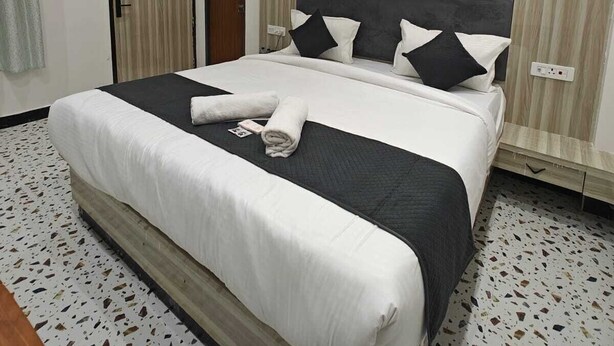A hotel room with a large bed, a ceiling fan, an air conditioning unit, and a door with a curtain. - The Shyama Grand Regency Ayodhya (Ayodhya)