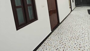 A hallway with white walls, a speckled floor, and wooden ceiling. - The Shyama Grand Regency Ayodhya (Ayodhya)
