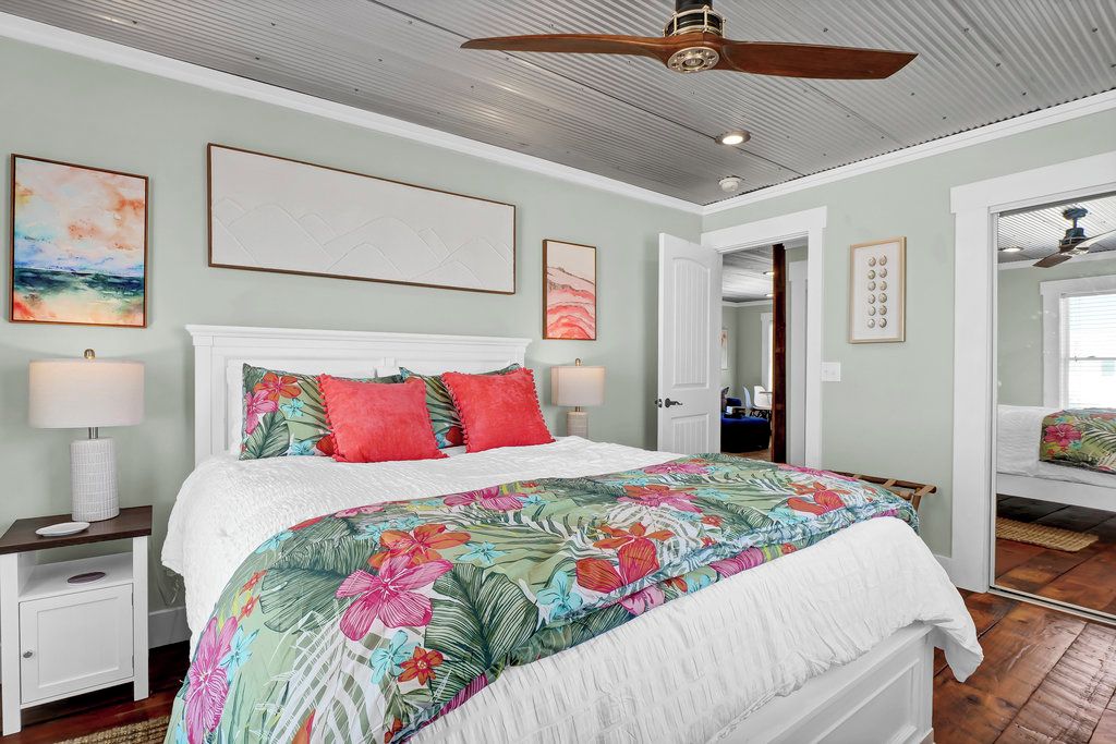 Une chambre à coucher avec un lit, un ventilateur de plafond et des œuvres d’art accrochées aux murs.