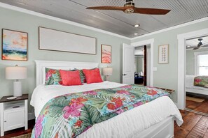 A bedroom with a bed, a ceiling fan, and artwork on the walls. - Coastal Cottage - Upscale 2 BR Condo at Mini Golf (Topsail Beach)