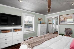 A bedroom with a bed, a television, a dresser, and a window with blinds. - Coastal Cottage - Upscale 2 BR Condo at Mini Golf (Topsail Beach)