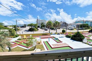 A residential area with houses, a parking lot, and a small garden with chairs. - Coastal Cottage - Upscale 2 BR Condo at Mini Golf (Topsail Beach)