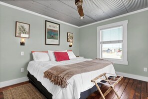 A bedroom with a bed, a window, and wall-mounted artwork.