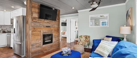 A modern living room with a fireplace, a sofa, and a television mounted on a wooden wall.