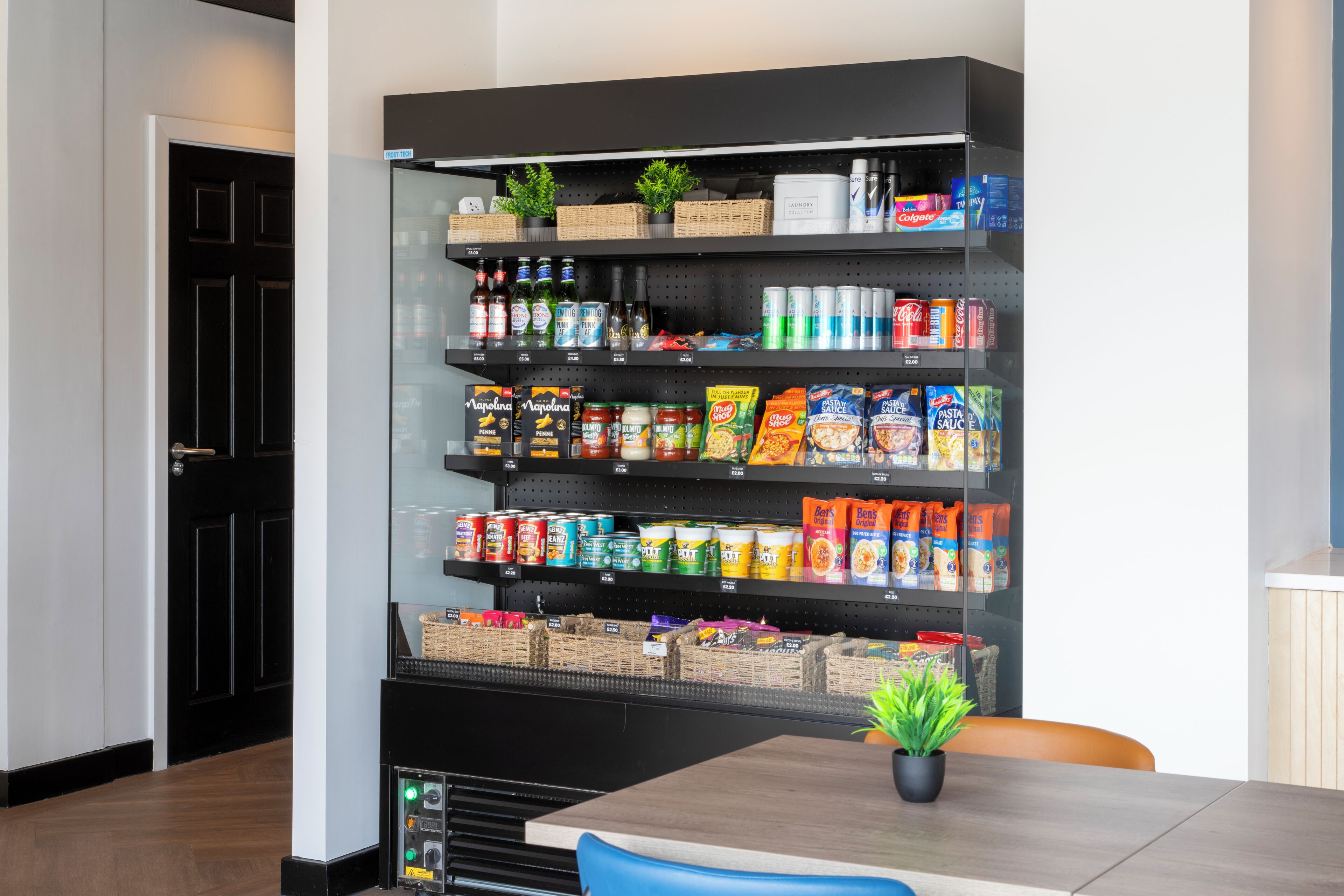 A kitchen with a black shelving unit stocked with various food items and beverages.