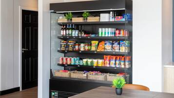 A kitchen with a black shelving unit stocked with various food items and beverages.