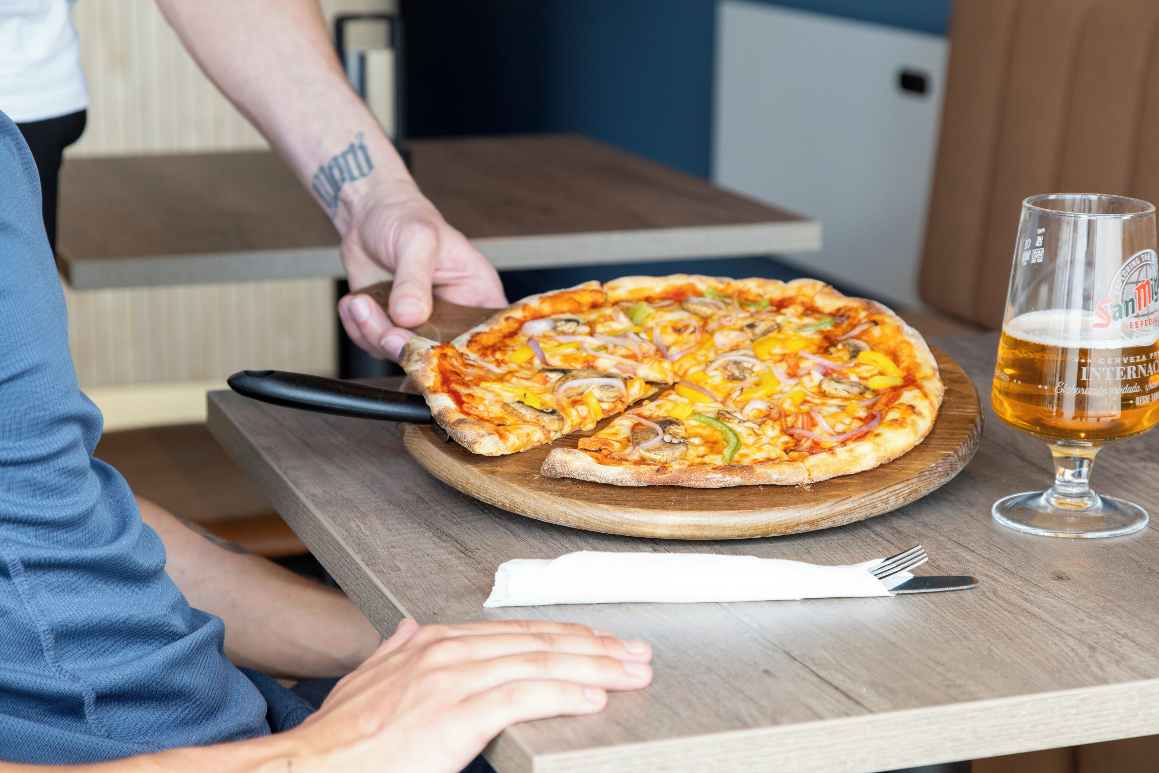 Pizza op een houten plank met een glas bier ernaast.