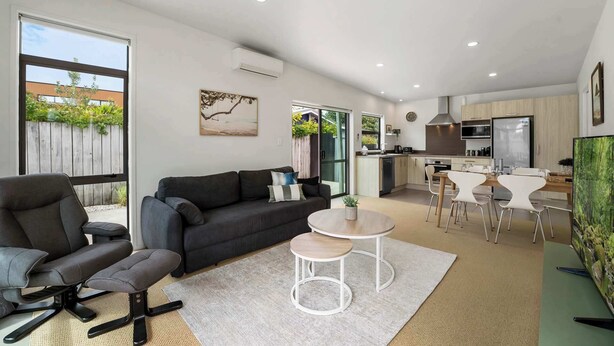 Un espacio habitable moderno con sofá, mesa de comedor y zona de cocina.