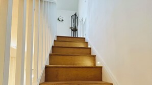 A wooden staircase with white railings and a wall-mounted light fixture.